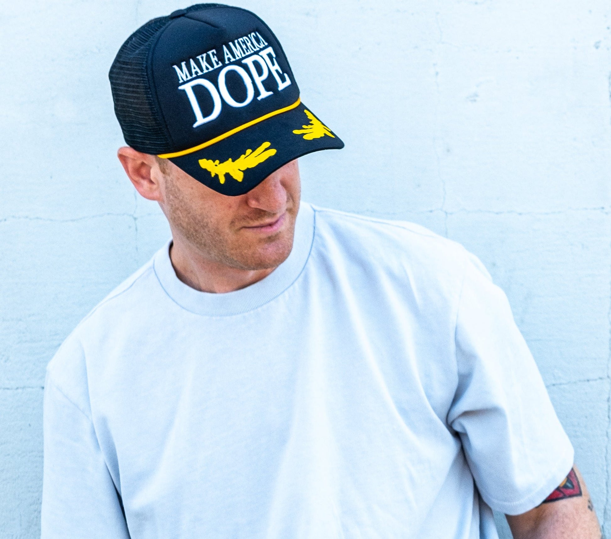 Man wearing black white and gold make america dope hat 