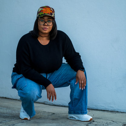 Woman wearing camoflage make america dope hat in front of wall