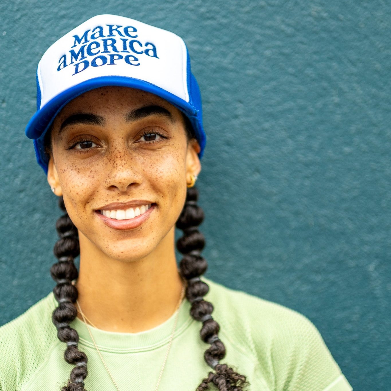 Smiling woman wearing blue and white Make America Dope Hat.