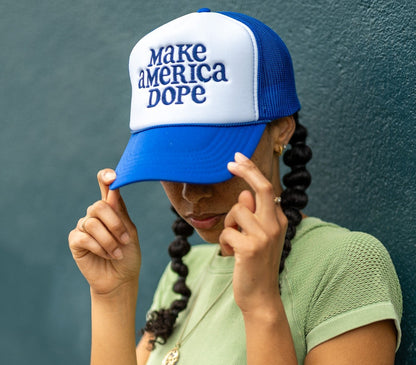 woman wearing blue and white make america dope hat in front of wall